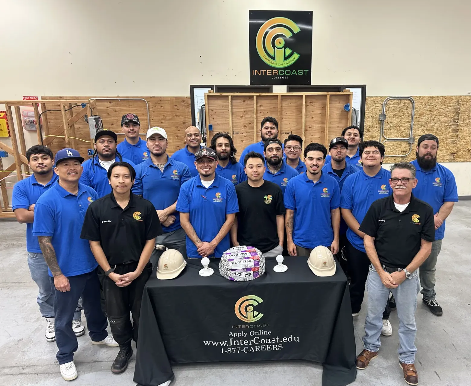 Electrical class and faculty at InterCoast's West Covina campus, standing in the training lab beneath the InterCoast logo